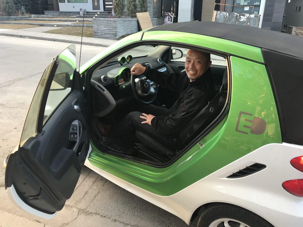 Ed Ma with his Smart EV Cabriolet in front of his solar thermal heated home in Calgary, Alberta. 